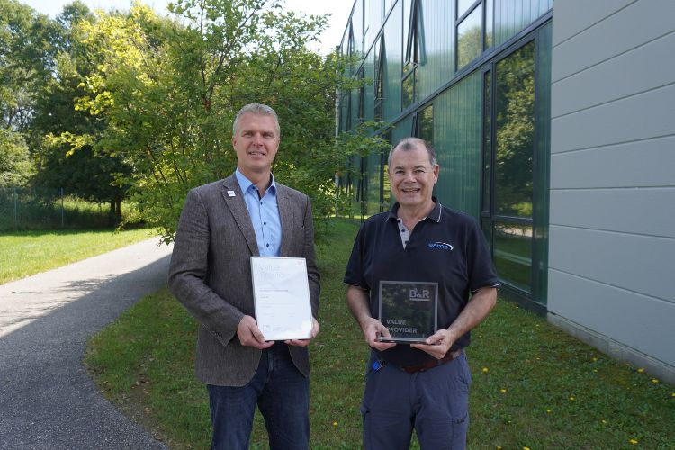 Two representatives from B&R and esmo automation present the official B&R Value Provider award in front of the company building.